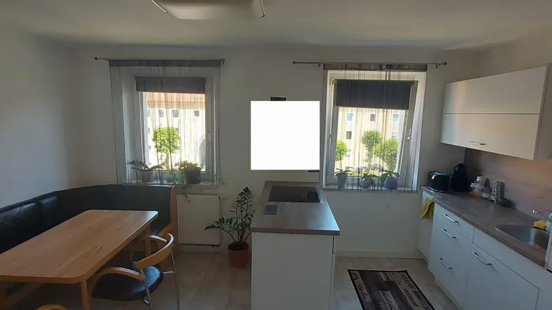 Helle Küche mit Essbereich, Einbauküche und Blick ins Grüne durch die Fenster.