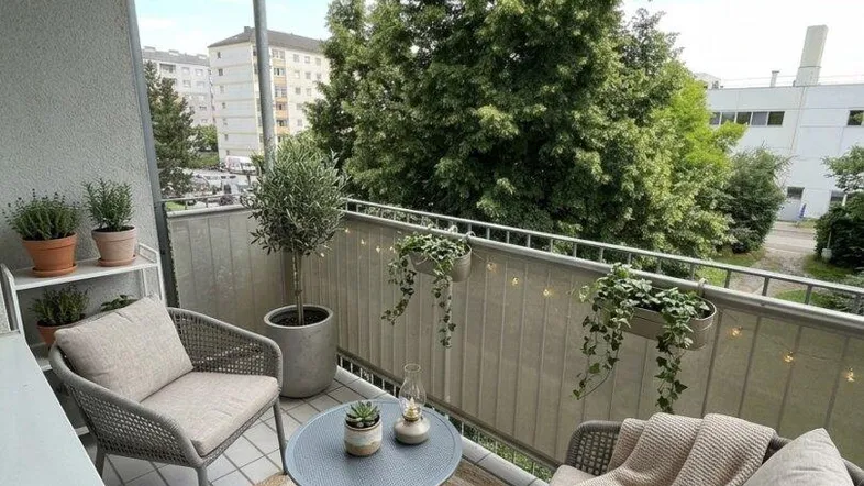 Gemütlicher Balkon mit Sitzgelegenheiten, Pflanzen und Blick ins Grüne.
