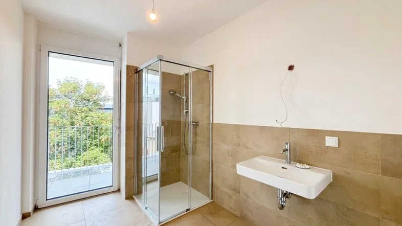 Modernes Badezimmer mit ebenerdiger Dusche, Waschbecken und Zugang zu einem Balkon.