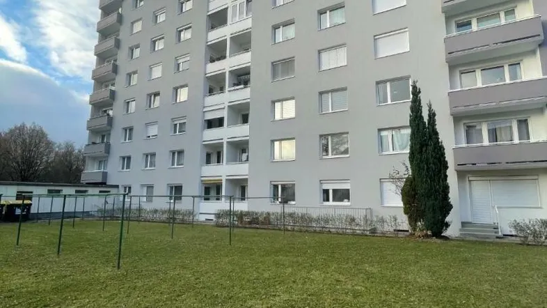 Modernes Mehrfamilienhaus mit zahlreichen Balkonen und einer gepflegten Rasenfläche im Vordergrund.