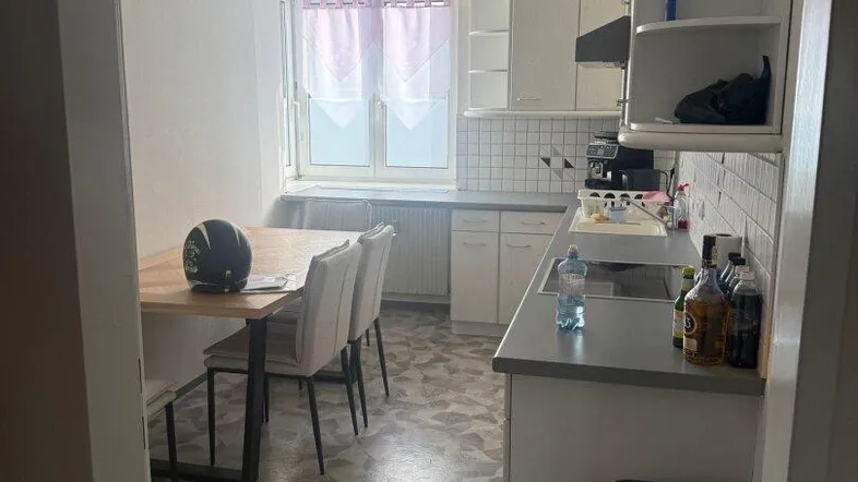 Helle Küche mit Essbereich, weißen Schränken und Fliesenboden, ideal für Mahlzeiten.