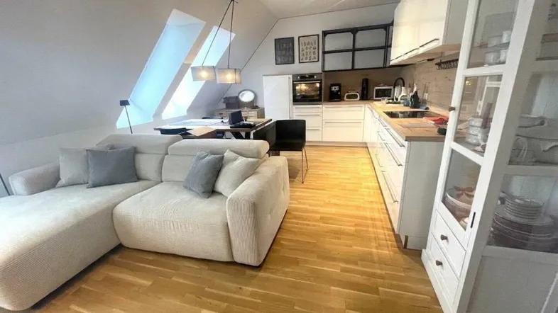 Heller offener Wohnbereich mit moderner Küche, gemütlichem Sofa und Dachfenstern.
