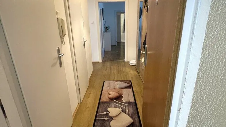 Heller Flur mit Laminatboden und Zugang zu verschiedenen Räumen der Wohnung.