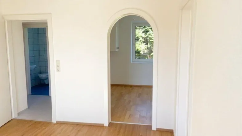 Heller Flur mit Holzboden, der zu einem Badezimmer und einem weiteren Raum führt.