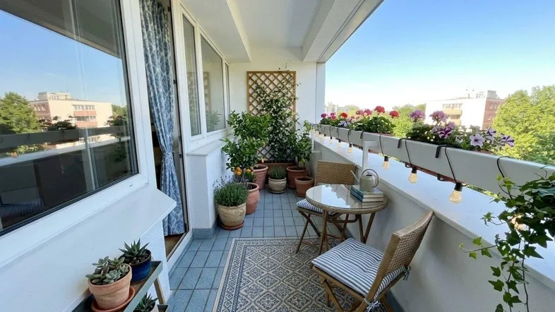 Helles, möbliertes Balkon mit Pflanzen, Blumenkästen und einem schönen Ausblick.