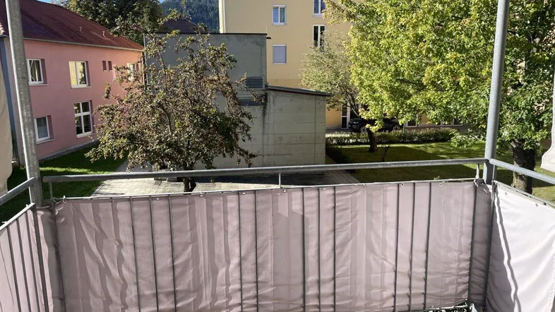 Blick vom Balkon auf den grünen Innenhof und die umliegenden Gebäude.
