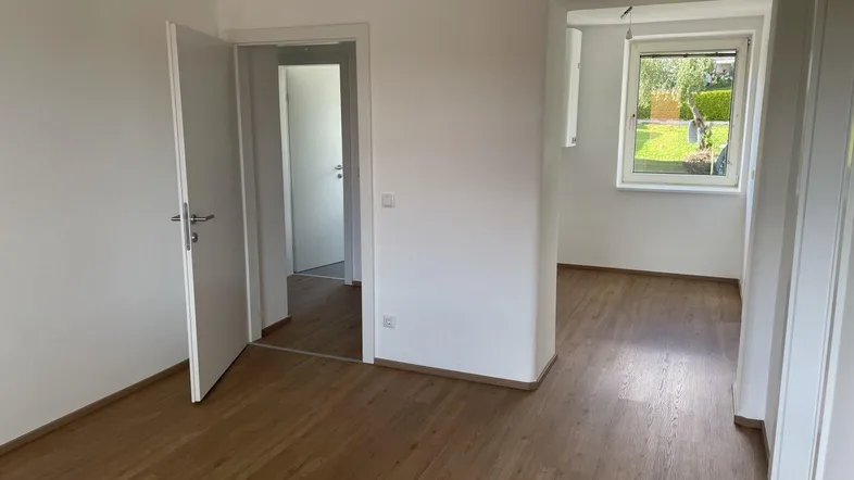 Heller Raum mit Laminatboden und Blick ins Grüne, ideal als Wohn- oder Schlafzimmer.