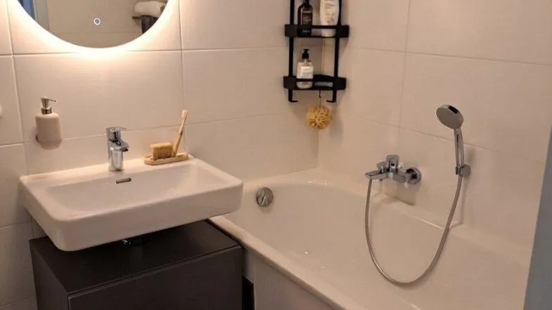 Modernes Badezimmer mit Badewanne, Waschtisch und beleuchtetem Spiegel.