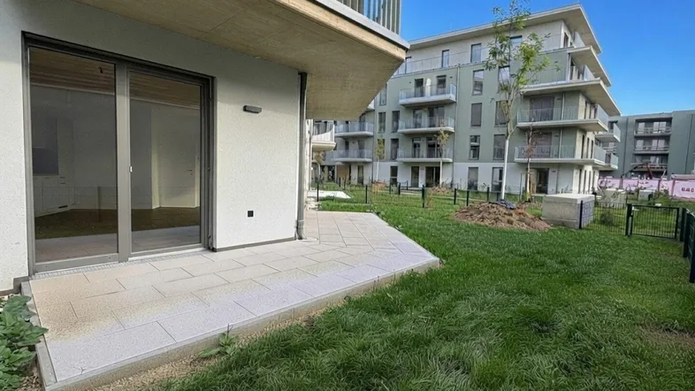 Blick auf die moderne Wohnanlage mit einer ebenerdigen Terrasse und angrenzendem Gartenbereich.