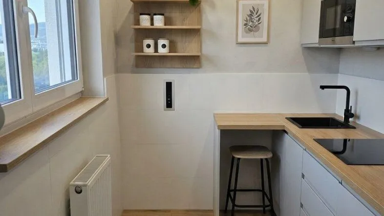 Moderne Küche mit hellen Schränken, Holzoptik-Arbeitsplatte und Fenster für Tageslicht.