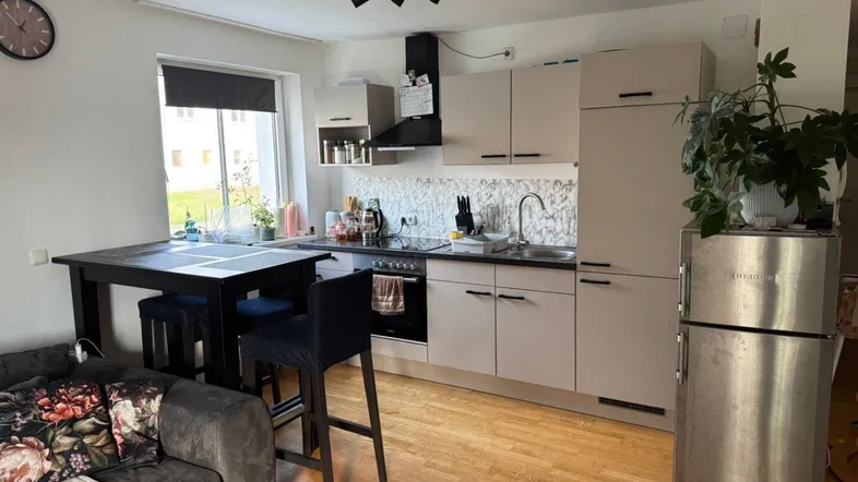 Moderne offene Küche mit Essbereich und angrenzendem Wohnbereich, ausgestattet mit Holzboden und Edelstahlkühlschrank.
