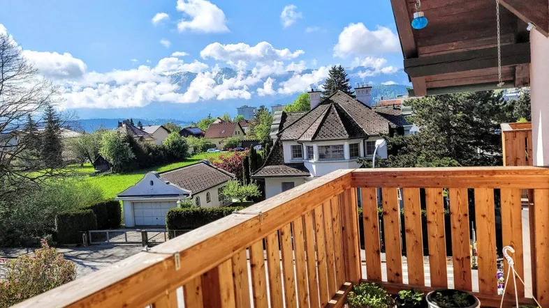Sonniger Balkon mit Holzgeländer und weitem Blick auf die umliegende Berglandschaft.