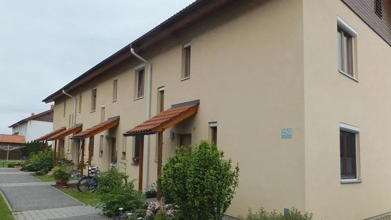 Reihenhäuser mit beiger Fassade, Satteldach und kleinen Vorgärten in einer Wohnsiedlung.