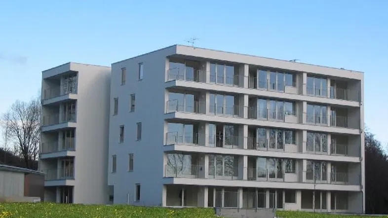 Modernes Mehrfamilienhaus mit klarer Architektur, großen Fensterfronten und zahlreichen Balkonen.