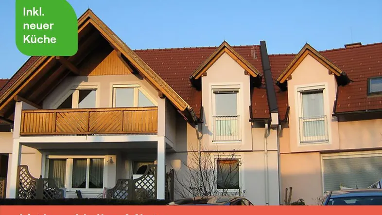 Mehrfamilienhaus mit Satteldach, Balkonen und Gauben, umgeben von einer ruhigen Wohngegend.