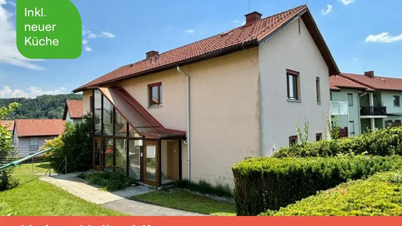 Außenansicht eines gepflegten Wohnhauses mit Satteldach, Glasanbau und grünem Gartenbereich.