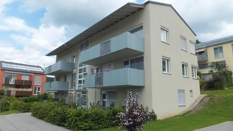 Modernes Mehrfamilienhaus mit Balkonen und Grünflächen in einer gepflegten Wohnsiedlung.
