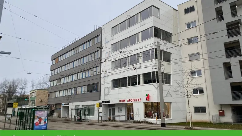 Modernes Geschäftsgebäude mit Apotheke im Erdgeschoss und großen Fenstern an einer belebten Straße.