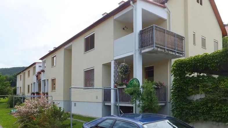 Mehrfamilienhaus mit mehreren Balkonen und gepflegter Außenanlage in grüner Umgebung.