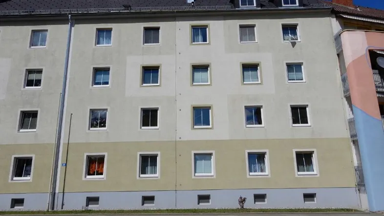 Mehrstöckiges Wohngebäude mit schlichter Fassade, vielen Fenstern und einem Satteldach.