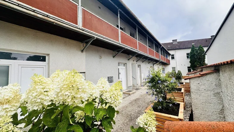 Innenhof mit bepflanzten Hochbeeten und Zugang zu den Wohneinheiten im Erdgeschoss und Obergeschoss.