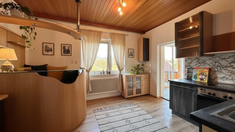 Offener Wohnbereich mit Holzbalkendecke, integrierter Bar und Blick ins Grüne.
