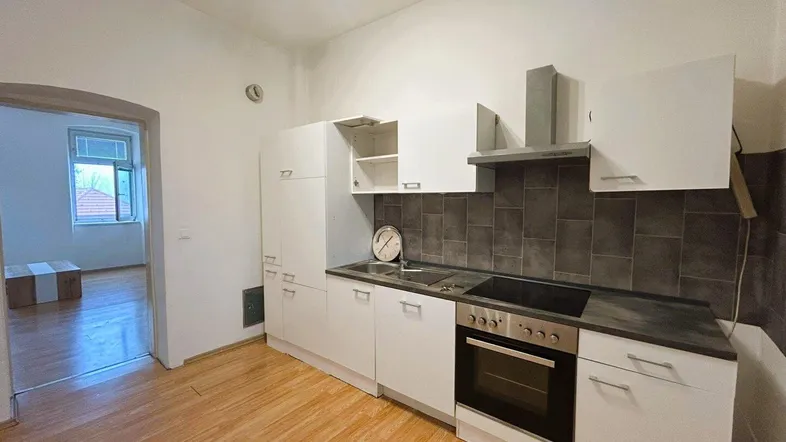 Funktionale Küche mit weißen Schränken, dunkler Arbeitsplatte und Laminatboden.