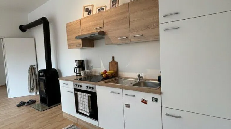 Funktionale Küche mit hellen Holz- und weißen Schränken, ausgestattet mit modernen Geräten und einem gemütlichen Teppich.