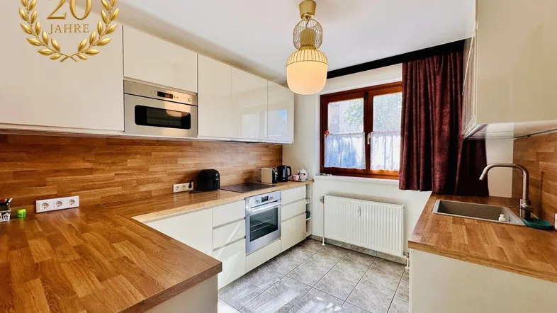 Helle Küche mit Holz-Arbeitsplatten, Einbaugeräten und einem Fenster, das natürliches Licht hereinlässt.
