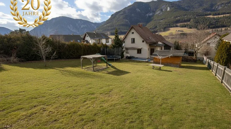 Großer Garten mit Rasenfläche, Spielgeräten und einem weiten Blick auf die umliegende Berglandschaft.