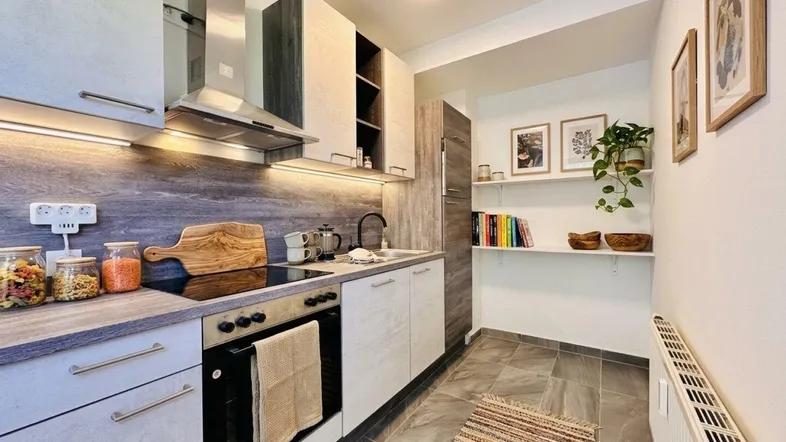 Moderne Küche mit Holzoptik-Arbeitsplatte, integriertem Kochfeld und praktischen Regalen.