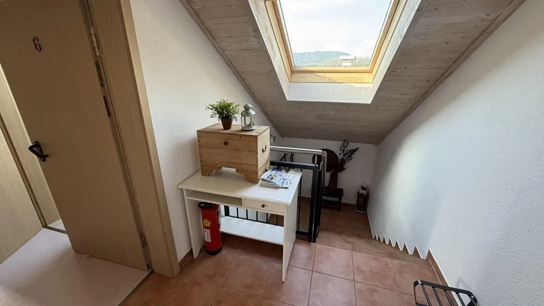 Dachgeschossflur mit Dachfenster, Holzboden und Zugang zu weiteren Räumen.