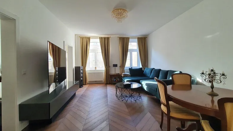 Geräumiger Wohn-Essbereich mit elegantem Fischgrätparkett, bequemer Couch und Esstisch.