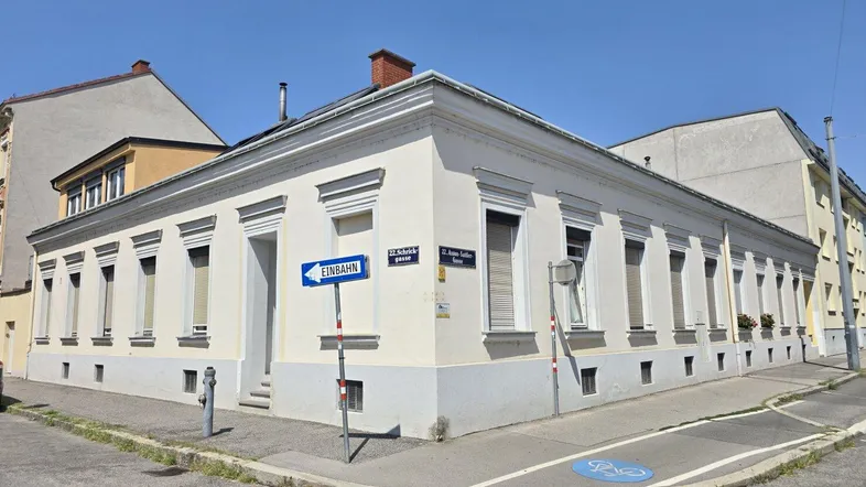 Historisches Eckgebäude mit klassischer Fassade und Fensterläden an einer sonnigen Straße.