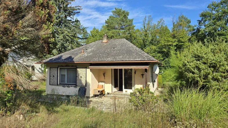 Kleines Haus mit Satteldach und umgebender Natur in sonniger Lage.