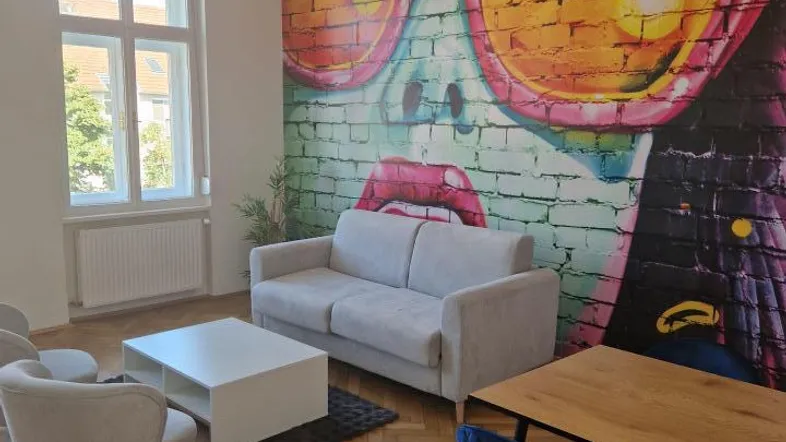 Helles Wohnzimmer mit modernem Wandbild, Parkettboden und bequemen Sitzgelegenheiten.