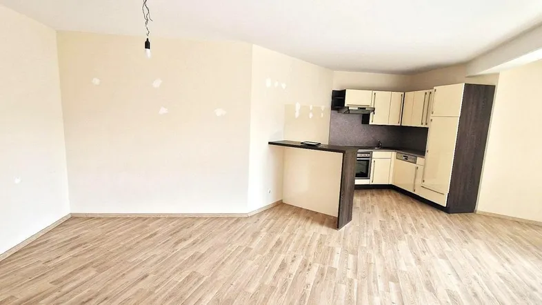 Heller offener Wohnbereich mit integrierter Küche, Bartheke und Laminatboden, ideal für modernes Wohnen.