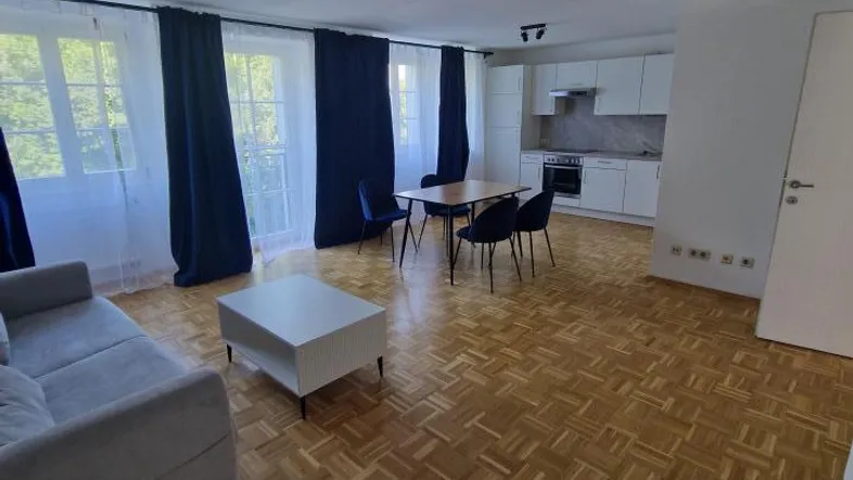 Helles, offenes Wohn-Esszimmer mit integrierter Küche und Parkettboden, ideal für geselliges Beisammensein.