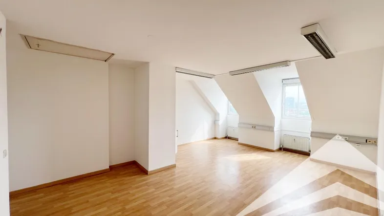 Geräumiger Dachgeschossraum mit Schrägdecken, Laminatboden und natürlichem Lichteinfall durch die Fenster.