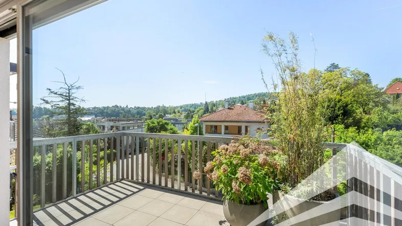 Großer Balkon mit Fliesenboden, Holzgeländer und weitem Blick ins Grüne.