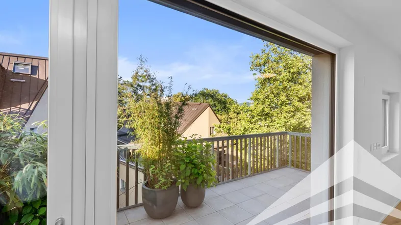 Helle Terrasse mit Fliesenboden und Pflanzen, umgeben von Bäumen und Häusern.