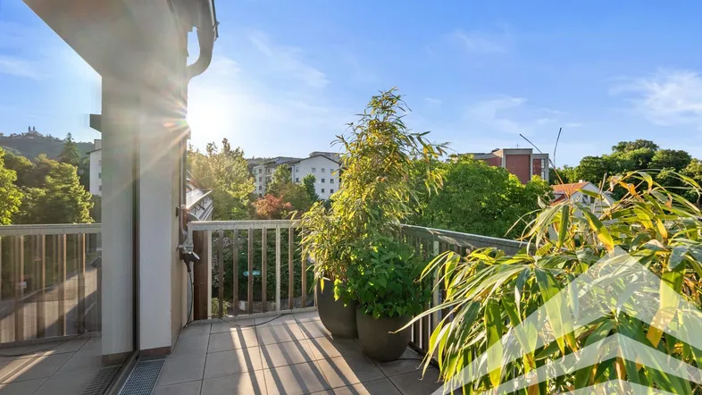 Sonniger Balkon mit Fliesenboden und Pflanzen, bietet einen weiten Blick über die Umgebung.