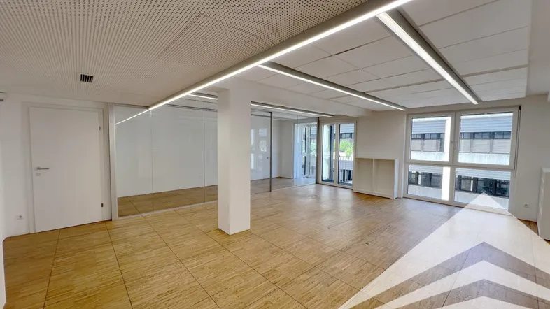 Geräumiges, modernes Büro mit Holzfußboden, Glaswänden und großen Fenstern, ideal für flexible Arbeitsbereiche.
