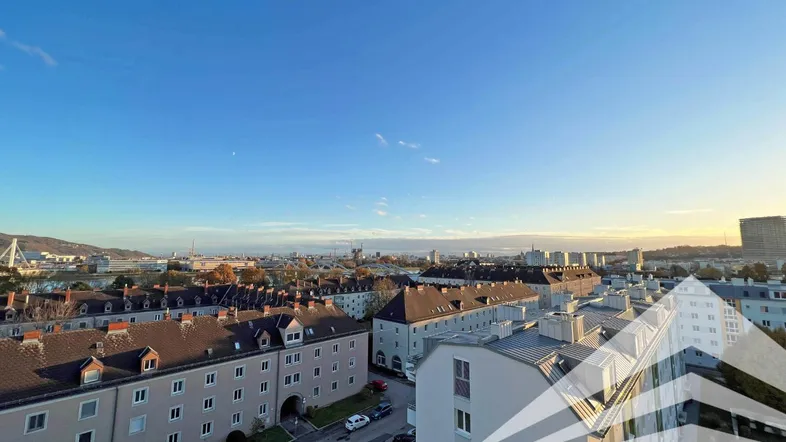 Weitläufiger Blick über die Stadt mit Fluss und umliegenden Gebäuden unter blauem Himmel.