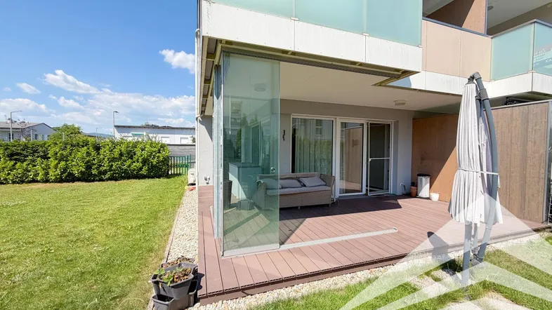 Geräumige Terrasse mit Holzdeck und Sitzgelegenheiten, umgeben von einem gepflegten Rasenbereich.