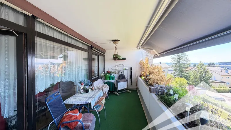 Geräumiger Balkon mit Sitzgelegenheiten, Pflanzen und Markise, bietet einen weiten Blick auf die Umgebung.