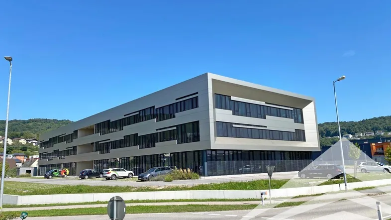 Modernes Geschäftsgebäude mit klarer Architektur und großen Fensterfronten unter blauem Himmel.