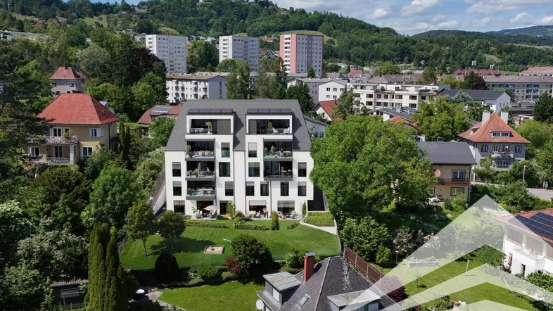 Moderne Wohnanlage mit mehreren Balkonen und Terrassen in grüner Hanglage mit Stadtblick.