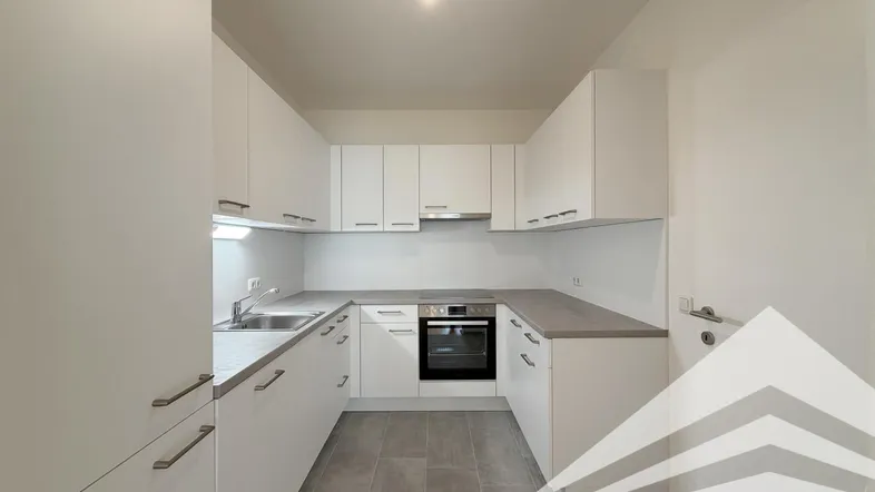 Moderne, helle Küche mit weißen Schränken, grauer Arbeitsplatte und Fliesenboden.