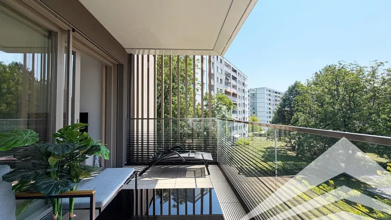 Geräumiger Balkon mit modernen Outdoor-Möbeln und Blick ins Grüne.